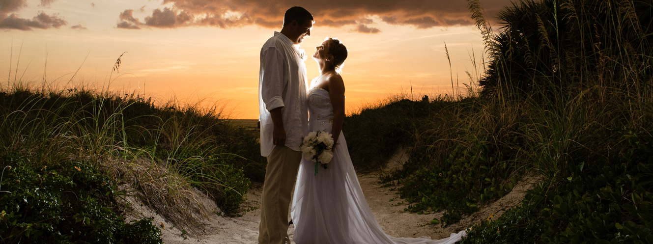Bride and Groom between the dunes at sunset gazing at each other