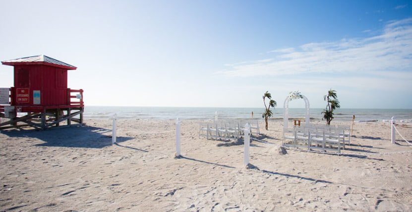 White rounded arch ceremony set up with lifeguard tower
